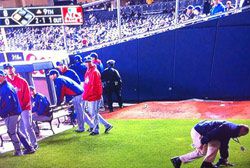 A stadium attendant picks up bottles thrown on the field during game 3 of the ALCS